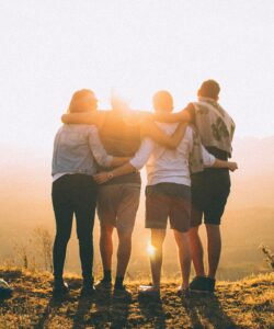 Group of four people hugging and watching the sunset