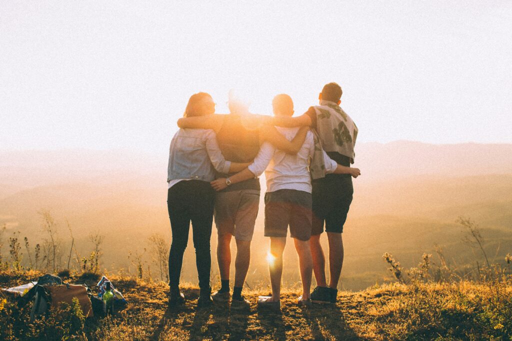 Group of four people hugging and watching the sunset