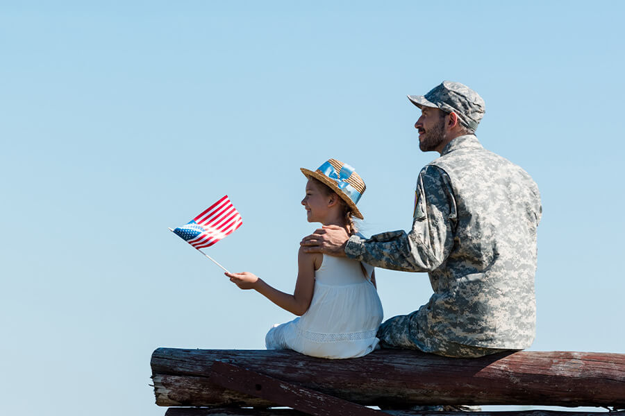 Soldier sitting with daughter who is waiving an American flag