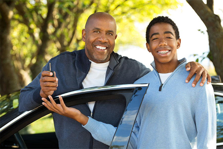 Dad and son posing in front of son's new car