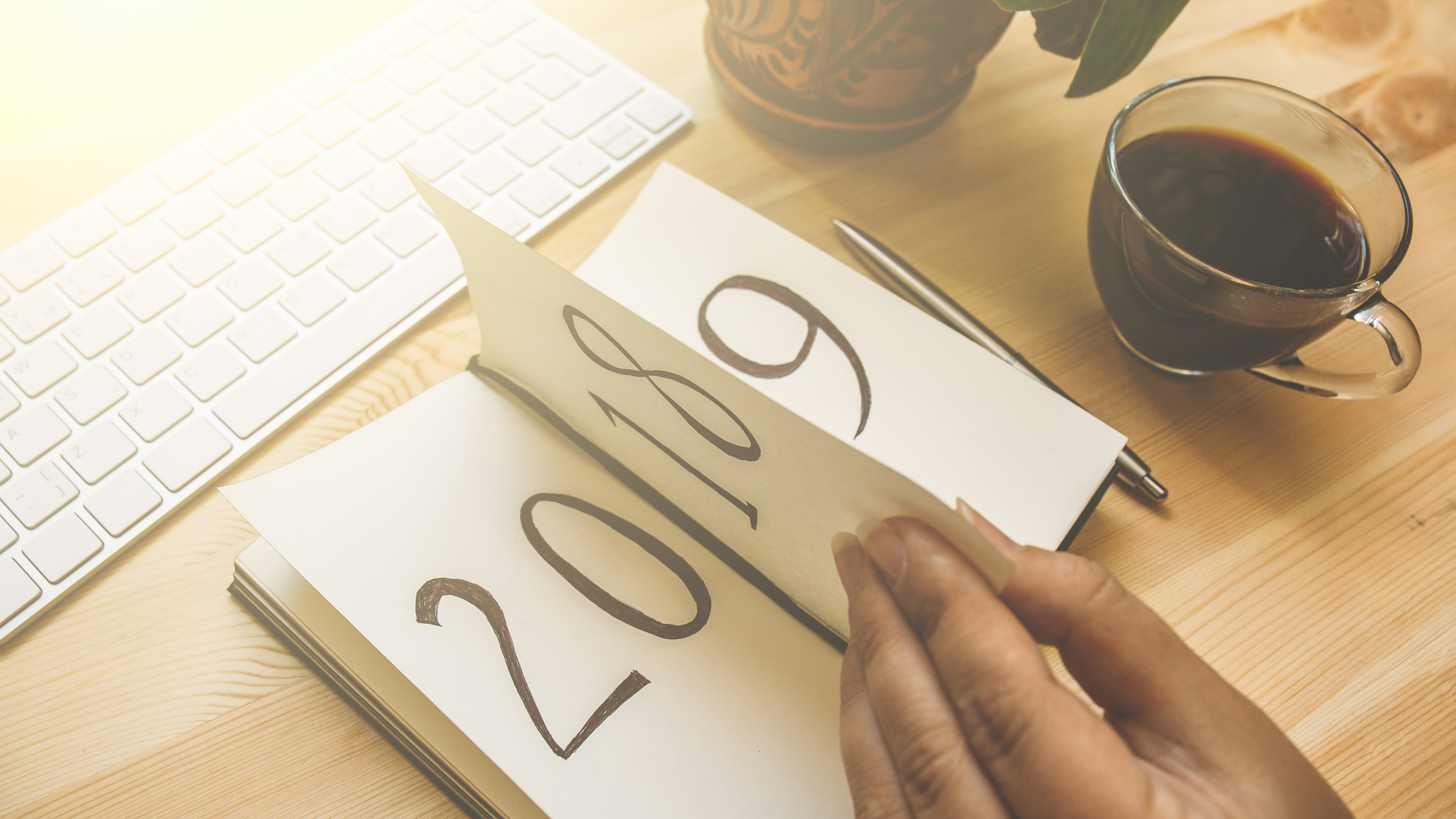 Person flipping a calendar from 2018 to 2019 on a desk