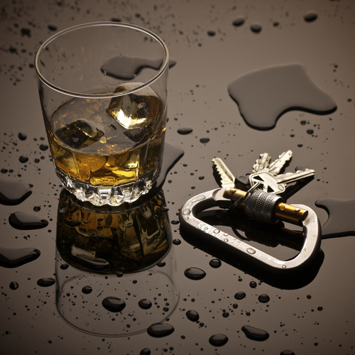 Hard Liquor and Car Keys sitting on a Bar with Spilled Liquid